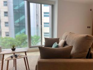 a couch in a living room with a large window at Luxury 1 Bed Apt - City Suites Ocean Spa Plaza in Gibraltar