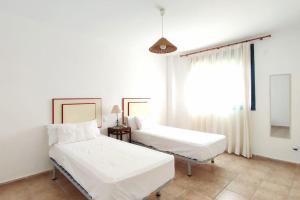 2 bedden in een witte kamer met een raam bij Terraza con vistas en Alcaidesa in Alcaidesa