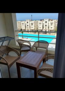 a table and chairs on a balcony with a swimming pool at قريه امواج الساحل الشمالى in Sīdī ‘Abd ar Raḩmān