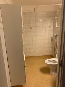 a bathroom with a toilet and a tiled wall at Charming Downtown Gem in Linköping