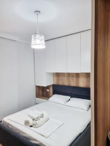 Un dormitorio con una cama blanca con toallas. en Hera's Home, en Tirana