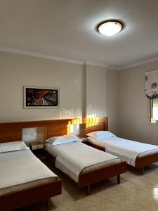 a bedroom with two beds and a ceiling with a light at AMI apartament in Vlorë