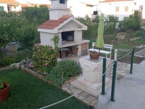 un patio trasero con una parrilla con una mesa y una sombrilla en Apartments Janjac, en Vodice