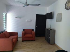 a living room with a couch and a chair and a tv at Garden Suites Comalcalco in Comalcalco