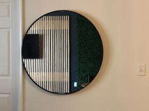 a round mirror on a wall with a green wall at EasyStays Alexandria in Alexandria