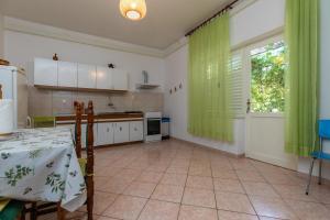 a kitchen with a table and a green curtain at Apartments by the sea Sumpetar, Omis - 949 in Jesenice