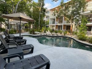 a pool with chairs and an umbrella next to a building at Erena Tulum in Tulum