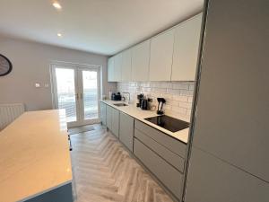 a kitchen with white cabinets and a wooden floor at The Dunes, Lytham St Annes in Lytham St Annes
