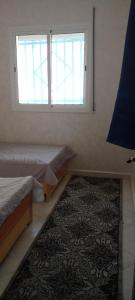a room with two beds and a window and a rug at Al Hoceima Badess in Al Hoceïma