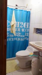 a bathroom with a toilet and a blue shower curtain at Habitación Triple Equipada, Posada Villa Mayo a 5 minutos de Playa Parguito in Loma de Guerra