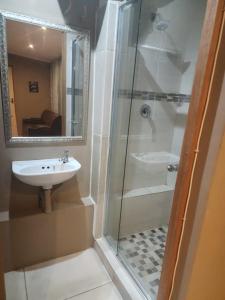 a bathroom with a glass shower and a sink at Charles Court Guest House in Durban