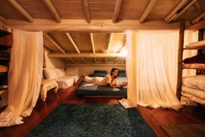 uma mulher deitada numa cama num quarto em Casinha Azul Caraíva - casa completa na beira do Rio em Caraíva