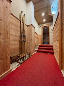 un corridoio con moquette rossa, con sci e tappeto rosso di Case Vacanza Perron a Sauze d'Oulx