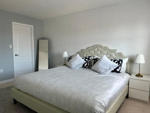 a bedroom with a white bed with black and white pillows at Cozy 5 Bedroom House Mississauga in Mississauga