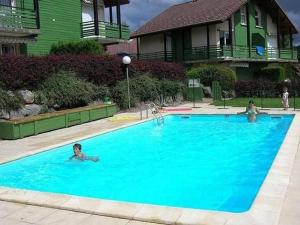 two people swimming in a large blue swimming pool at Appartement avec Terrasse & Piscine Privée, Gérardmer - FR-1-589-56 in Gérardmer