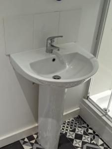 a white sink in a bathroom with a black and white floor at The Cosy Beach in Llanelli