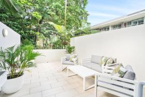 パーム・コーブにあるHotel Drift 3205 Beachfront Accomodationの白い家具と植物のある屋外パティオ