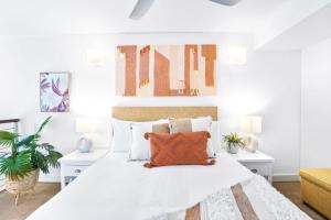 Dormitorio blanco con cama blanca y almohadas de color naranja en Hotel Drift 3205 en Palm Cove