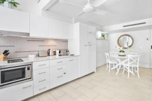 パーム・コーブにあるHotel Drift 3205 Beachfront Accomodationの白いキッチン(テーブル、天井ファン付) +13枚の写真
