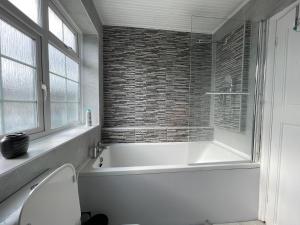 a white bathroom with a tub and a window at Luxurious Detached Holiday House Free Parking near Airport Town Centre Railway Station in Luton