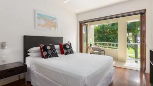 a bedroom with a white bed and a large window at Watermark Villa Port Douglas in Port Douglas