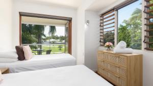 een slaapkamer met 2 bedden en een groot raam bij Watermark Villa Port Douglas in Port Douglas