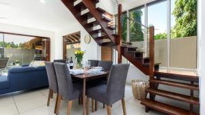 a dining room with a table and a spiral staircase at Watermark Villa Port Douglas in Port Douglas