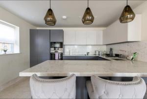 a kitchen with a counter and two white chairs at 2BD, 2BA Urban Oasis CHCL F4 in Chigwell