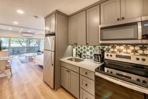 a kitchen with stainless steel appliances and a living room at Newly Renovated Studio on First Floor in Quiet Complex Across the Street from the Beach in Kihei