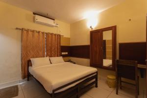 a small bedroom with a bed and a mirror at JK Lodge in Kottayam