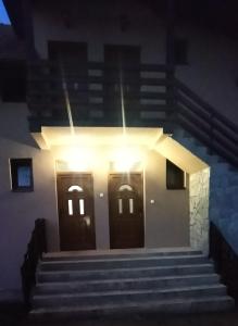 a building with two doors and stairs at night at Apartman NIKOLIJA 2 in Kaludjerske Bare
