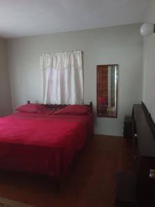 1 dormitorio con cama roja y ventana en Campbell's living accommodations. en Gwa Kay