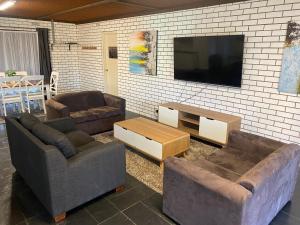 uma sala de estar com 2 sofás e uma televisão de ecrã plano em Tatura Country Motel em Tatura