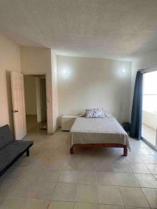 a bedroom with a bed and a couch and a window at Casa Caleta renta para Vacaciones a 10minplaya in Acapulco