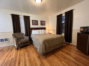 ein Schlafzimmer mit einem Bett, einem Stuhl und einem TV in der Unterkunft The Cascade Motel in Cascade Locks