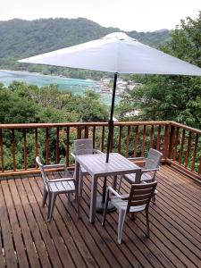 a table and chairs on a deck with an umbrella at Cabana El Caney in Sapzurro