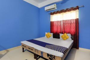 a bedroom with a bed with blue walls and a window at SPOT ON New Modern Guest House in Varanasi