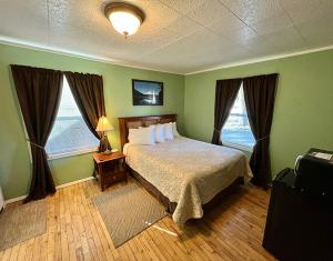 1 dormitorio con 1 cama y 2 ventanas en The Cascade Motel, en Cascade Locks
