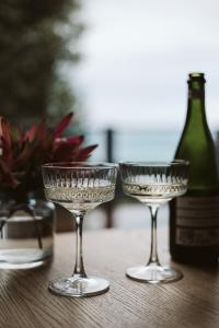 três copos sentados numa mesa com uma garrafa de vinho em Point of View Villas em Apollo Bay