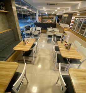 a restaurant with wooden tables and white chairs at Hotel Pousada Posto Carvalho in Campo Formoso