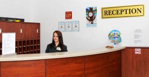 Una mujer está sentada en un mostrador de recepción. en Hostel Malibu, en Sunny Beach