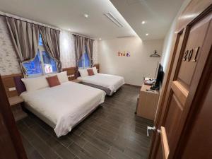 um quarto de hotel com duas camas e uma televisão em 陽光小灣旅店 em Kenting