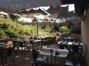 un patio con mesas y sillas bajo una sombrilla blanca en Aux Terrasses, en Tournus