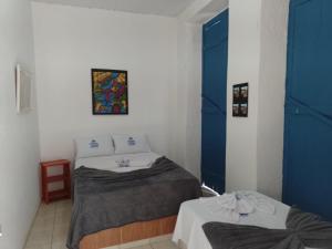 twee bedden in een kamer met blauwe deuren bij Pouso das Artes Cachoeira-hospedaria e espaço cultural in Campinas