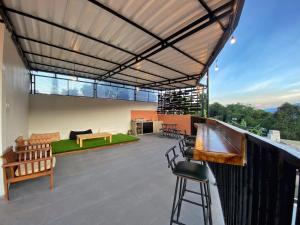 a large patio with a roof with a bar and chairs at villa view2 sayriah in Puncak