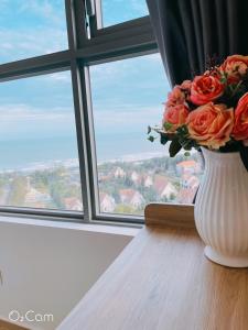 a vase with a bouquet of orange roses in a window at CĂN HỘ 5 SAO THE SÓNG VŨNG TÀU- CONDOTEL 5 STAR THE SÓNG APARTMENT Mr VƯƠNG. in Vung Tau
