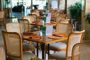 a row of wooden tables and chairs in a restaurant at Crystalkuta Hotel - Bali in Kuta