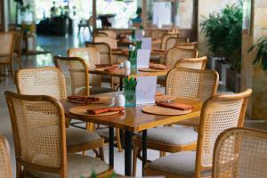 uma fila de mesas e cadeiras de madeira num restaurante em Crystalkuta Hotel - Bali em Kuta