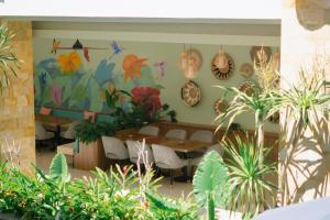 a restaurant with tables and plants in a room at Crystalkuta Hotel - Bali in Kuta