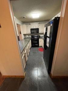 a kitchen with a black refrigerator and white cabinets at SPECIAL RATE Golfer's Paradise & 10 Minutes to Rocky Top Sports in Gatlinburg